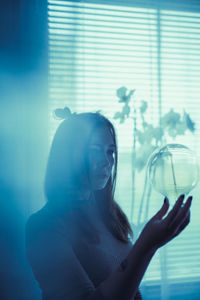 Portrait of young woman looking through window