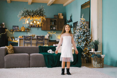 Full length of young woman standing on sofa