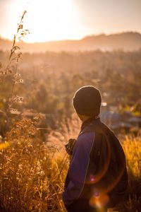 Rear view of man on field against sky during sunset