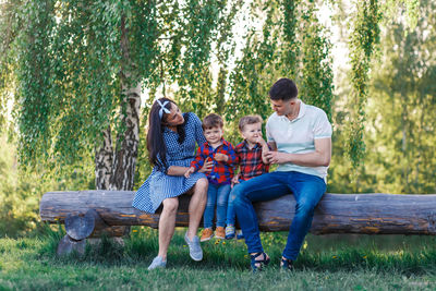 Full length of father and daughter sitting on swing