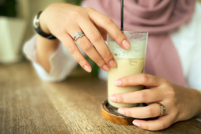 Midsection of women holding glass of coffee