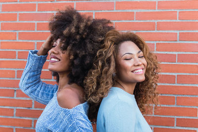 Portrait of african natural girls standing back to back with eyes closed