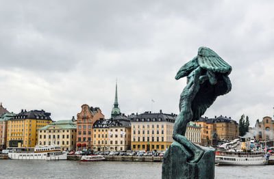 Statue in city against cloudy sky