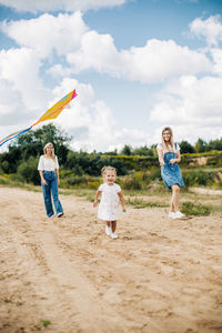 A happy family is preparing to fly a kite. the female part of the family launches a kite