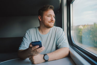 A man using a smartphone while traveling by railway train