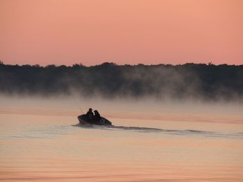 Scenic view of lake against sky during sunset with fisherman boat 