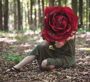 Midsection of woman with red roses in forest