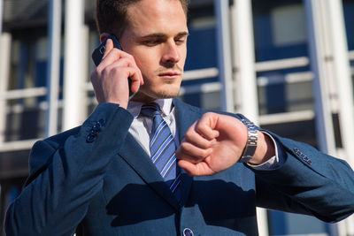 Low angle view of businessman talking on smart phone while standing against building