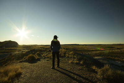 Rear view of man standing on field against sky