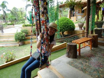 Portrait of happy young woman on tree trunk