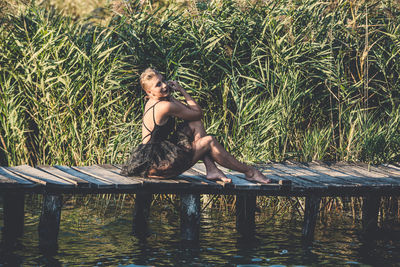 Woman sitting on wood by plants