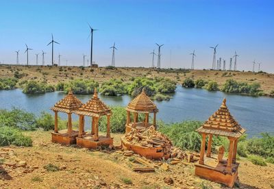 High angle view of gazeboes by lake against clear blue sky