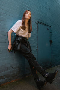 Portrait of young woman standing against wall