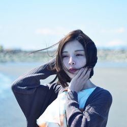 Portrait of beautiful young woman standing against sky