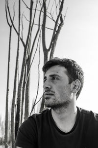 Portrait of young man looking away against sky