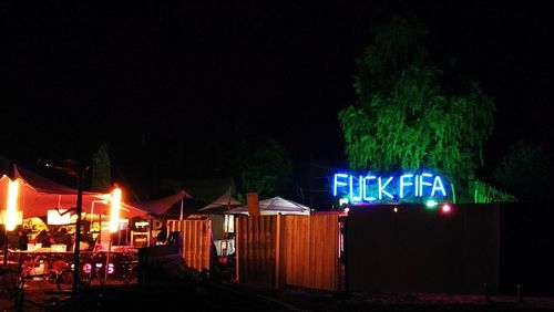 Illuminated city street against sky at night