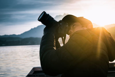 Man photographing with camera against sky