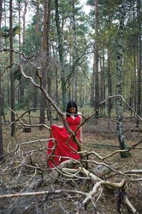 Red man standing by tree trunk in forest