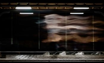 Blurred motion of woman seen through train window at railroad station