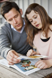 Father helping daughter understand while reading book