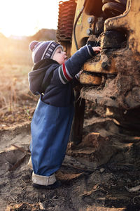 Side view of baby boy standing by truck