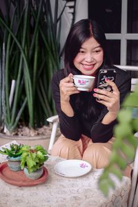 Young woman using mobile phone while sitting on table
