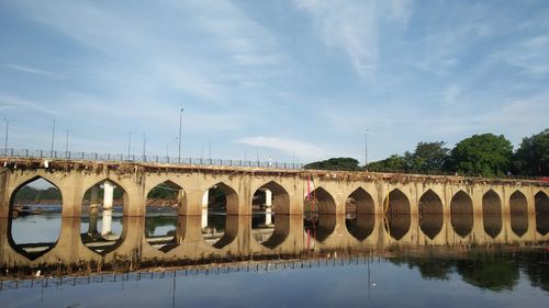 Arch bridge over river against sky