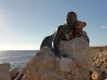 Statue by sea against clear sky