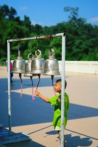 Close-up of child hanging on tree against sky