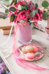 High angle view of macaroons in plate by flower vase on table