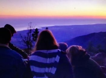 Rear view of people looking at mountain during sunset