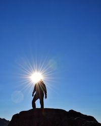 Low angle view of silhouette person standing against blue sky