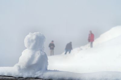 Rear view of people walking on snow against sky