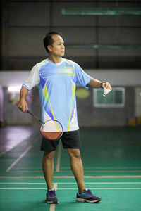 Full length of young man holding ball while standing against the background