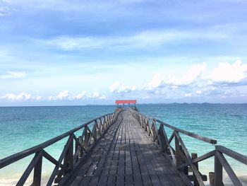 Pier on sea against cloudy sky