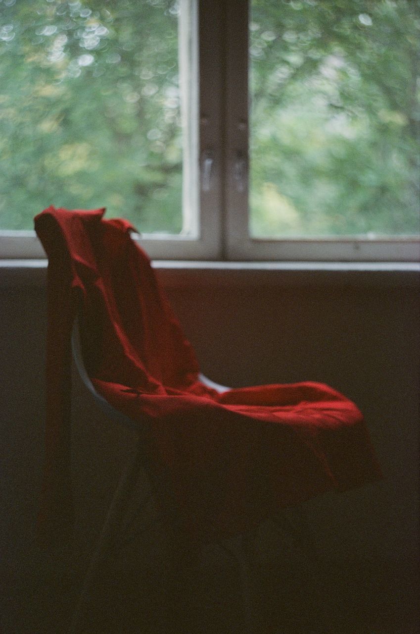 CLOSE-UP OF RED GLASS WINDOW AGAINST CURTAIN AT HOME