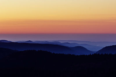 Scenic view of silhouette mountains against orange sky