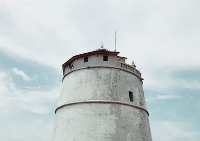 Low angle view of lighthouse by building against sky