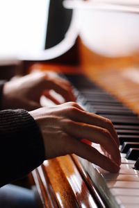 Close-up of hands playing piano at home