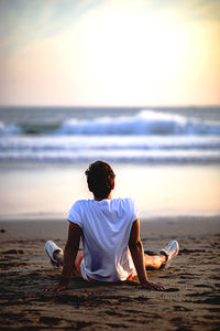 Rear view of man sitting on beach