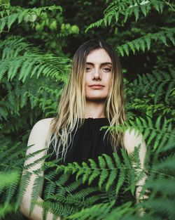 Portrait of young woman standing against plants