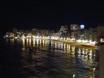 Illuminated cityscape against sky at night