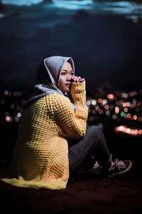 Thoughtful woman wearing hijab sitting outdoors