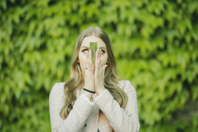 Beautiful woman holding crystal praying against plants