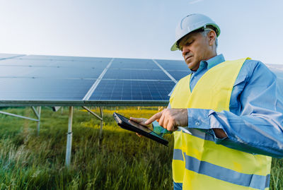 Solar engineer working with digital tablet at renewable energy farm. alternative eco energy concept