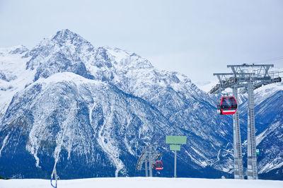 Overhead cable cars against snow covered mountain