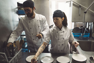 Male and female chefs working at kitchen counter