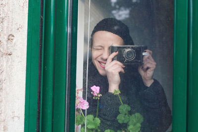 Close-up of woman photographing seen through window