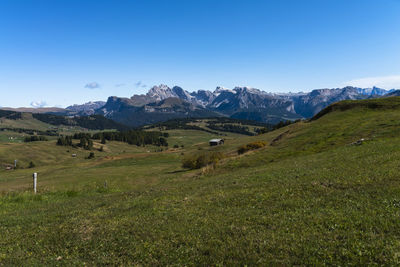 Scenic view of field and mountains against blue sky