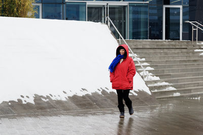 Rear view of woman walking on wet street in city